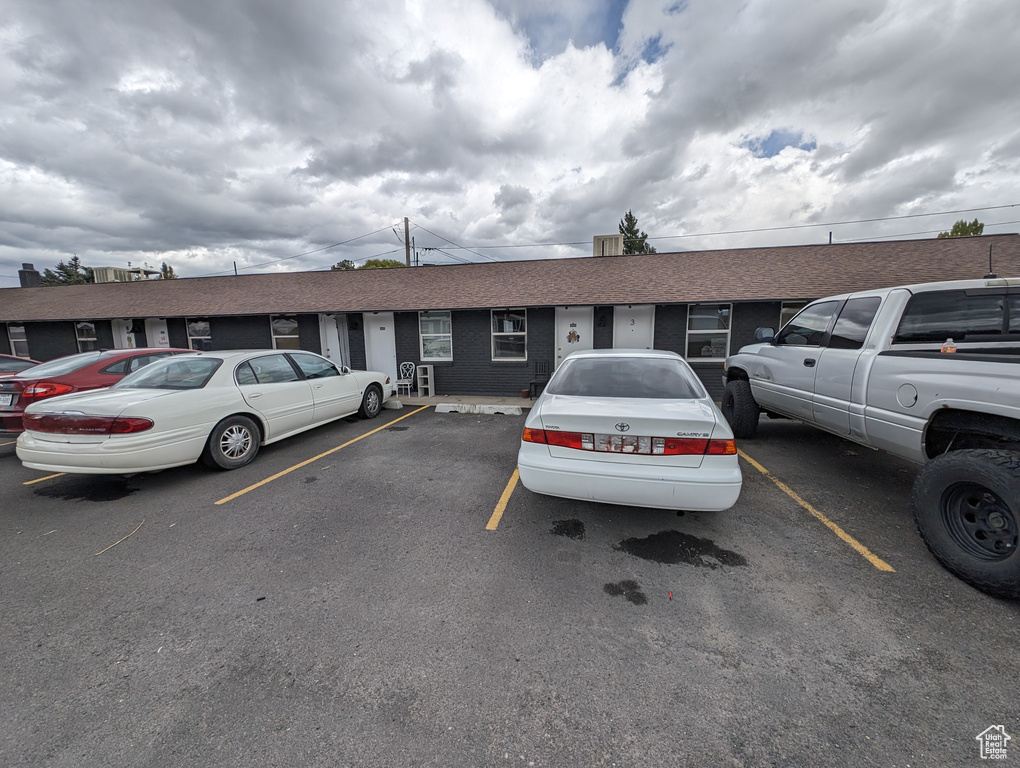 View of front of property featuring uncovered parking and roof with shingles