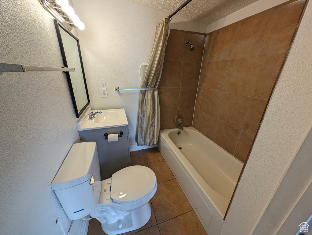 Full bathroom with shower / bath combo with shower curtain, tile patterned floors, a textured wall, and toilet