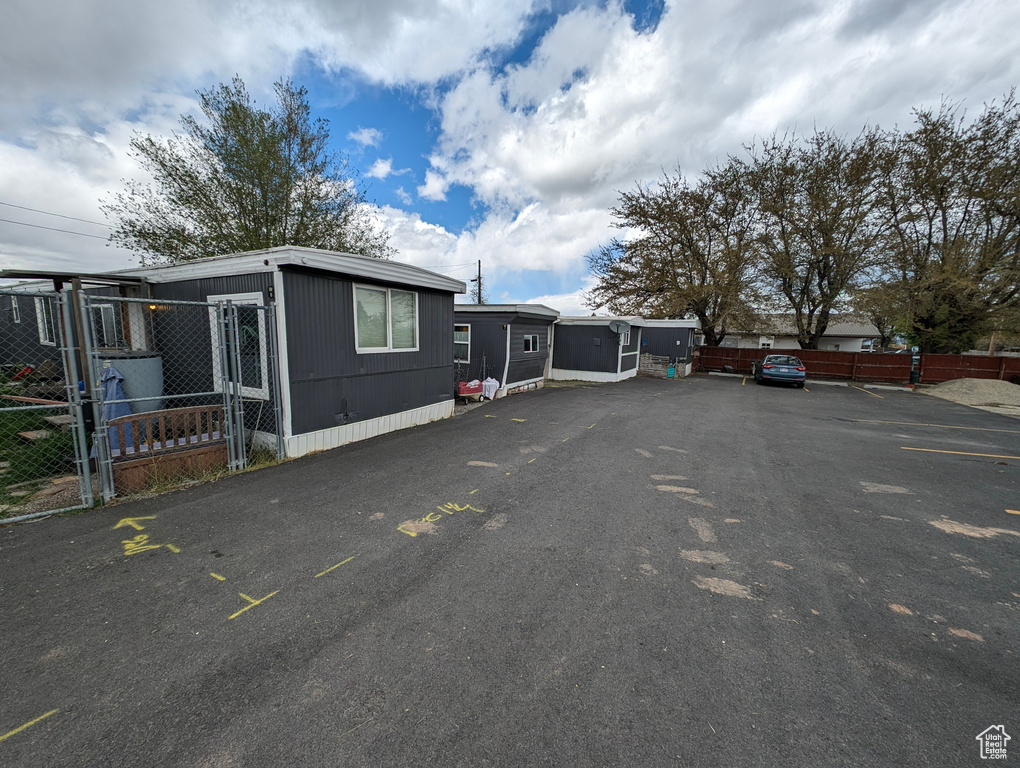 View of side of home with fence and uncovered parking