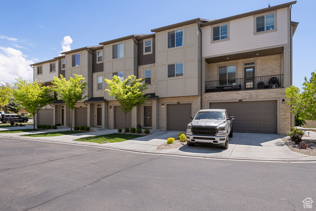 Townhome / multi-family property featuring concrete driveway, stone siding, and a garage