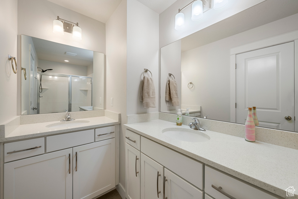 Bathroom featuring a sink, a shower stall, and two vanities