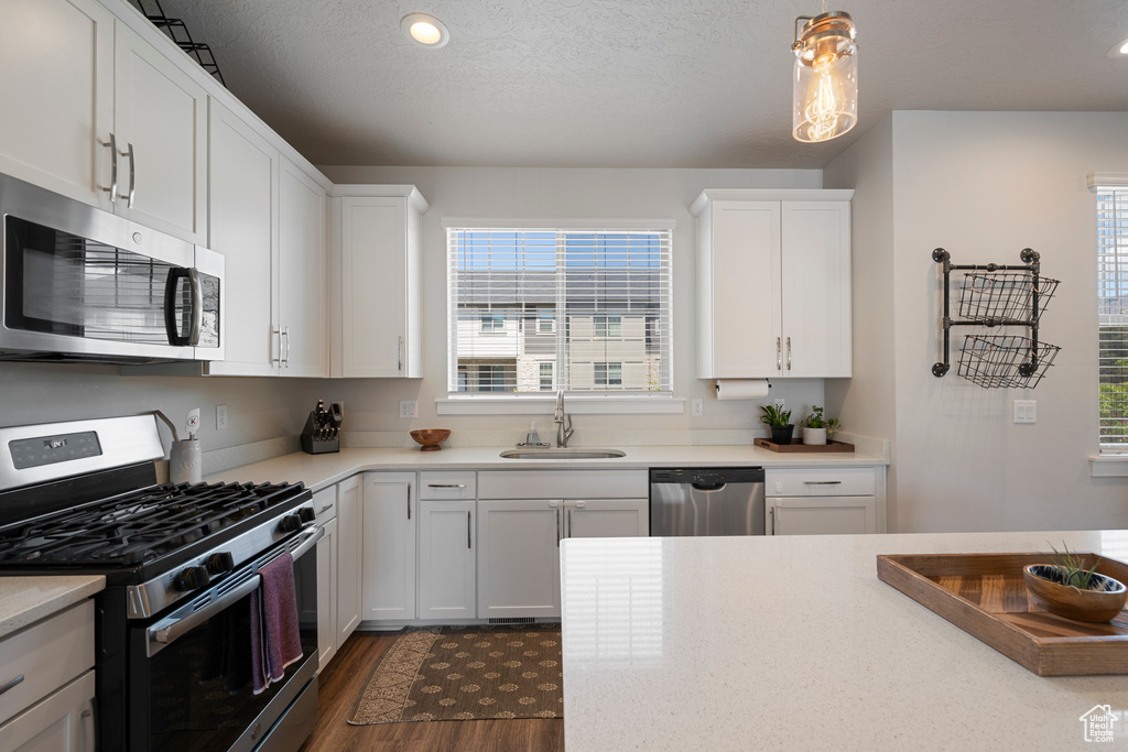 Kitchen with a sink, appliances with stainless steel finishes, a healthy amount of sunlight, and light countertops