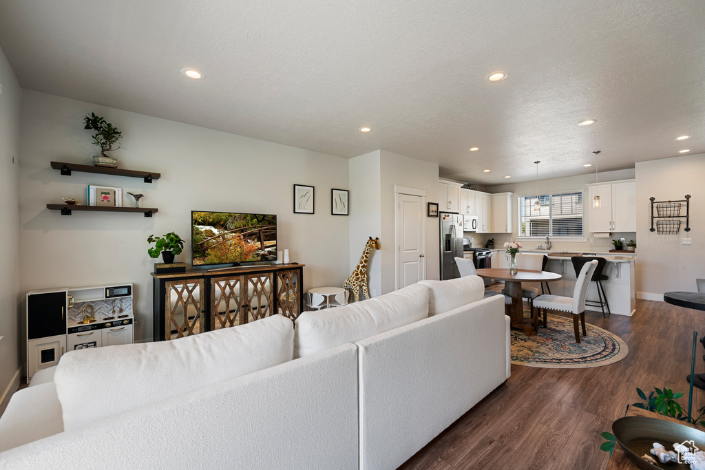 Living room featuring baseboards, recessed lighting, and dark wood-style floors
