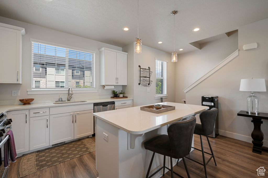 Kitchen featuring dark wood-type flooring, a sink, a breakfast bar area, and a healthy amount of sunlight