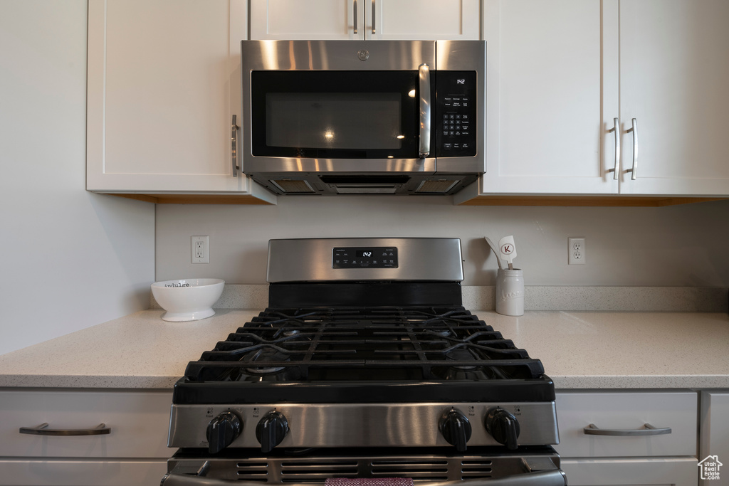 Kitchen featuring light stone counters, white cabinets, and stainless steel appliances