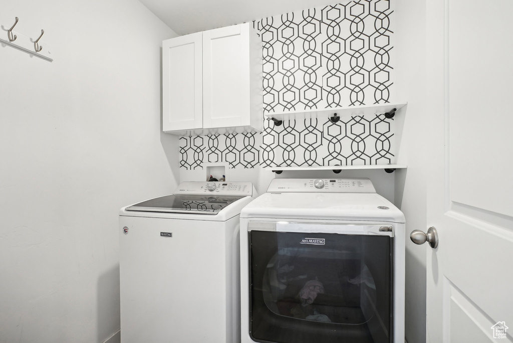Washroom featuring cabinet space and washing machine and clothes dryer
