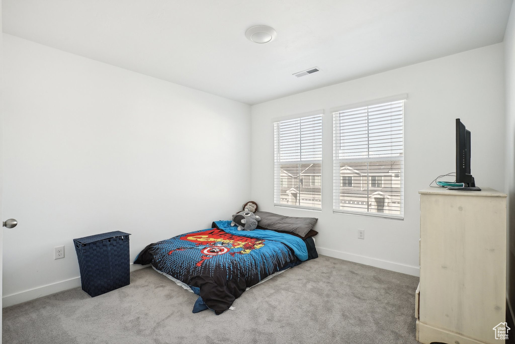 Carpeted bedroom with baseboards and visible vents