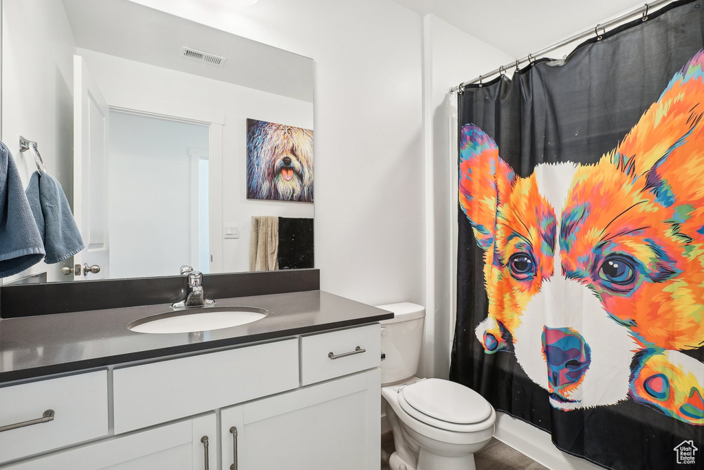 Bathroom featuring vanity, curtained shower, visible vents, and toilet