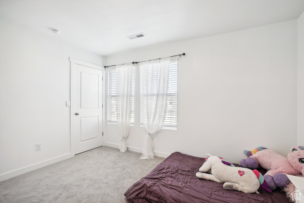 Carpeted bedroom featuring baseboards and visible vents