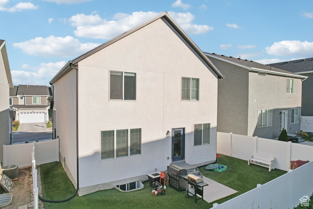 Rear view of property with a lawn, stucco siding, and a fenced backyard