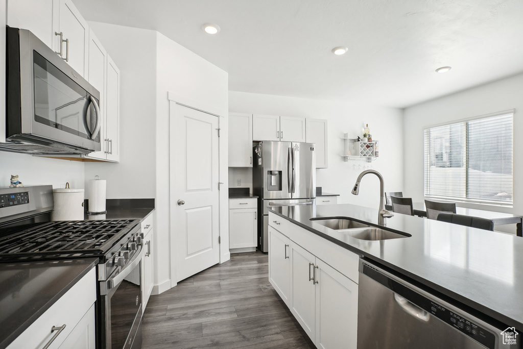 Kitchen featuring a sink, appliances with stainless steel finishes, white cabinets, and dark countertops