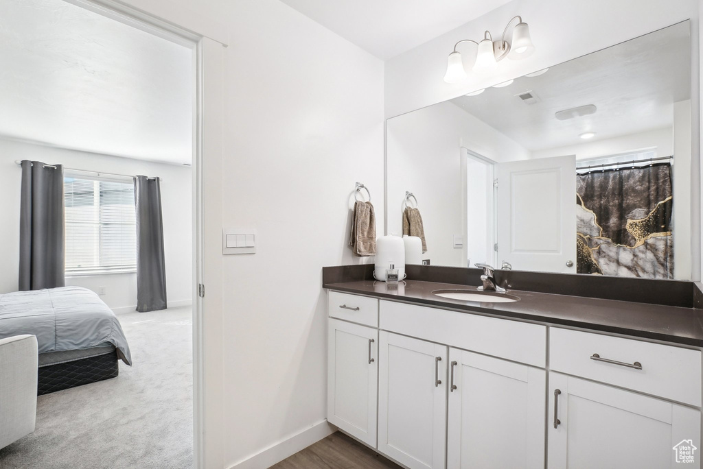 Bathroom featuring vanity, baseboards, ensuite bath, and visible vents