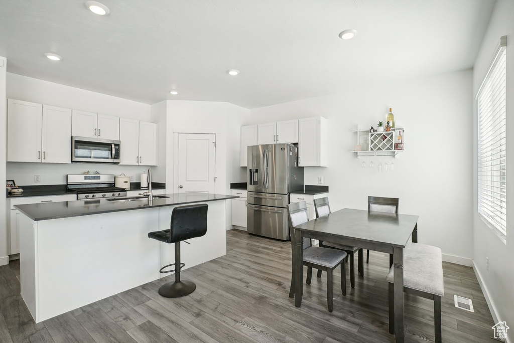 Kitchen featuring dark countertops, appliances with stainless steel finishes, visible vents, and dark wood-type flooring