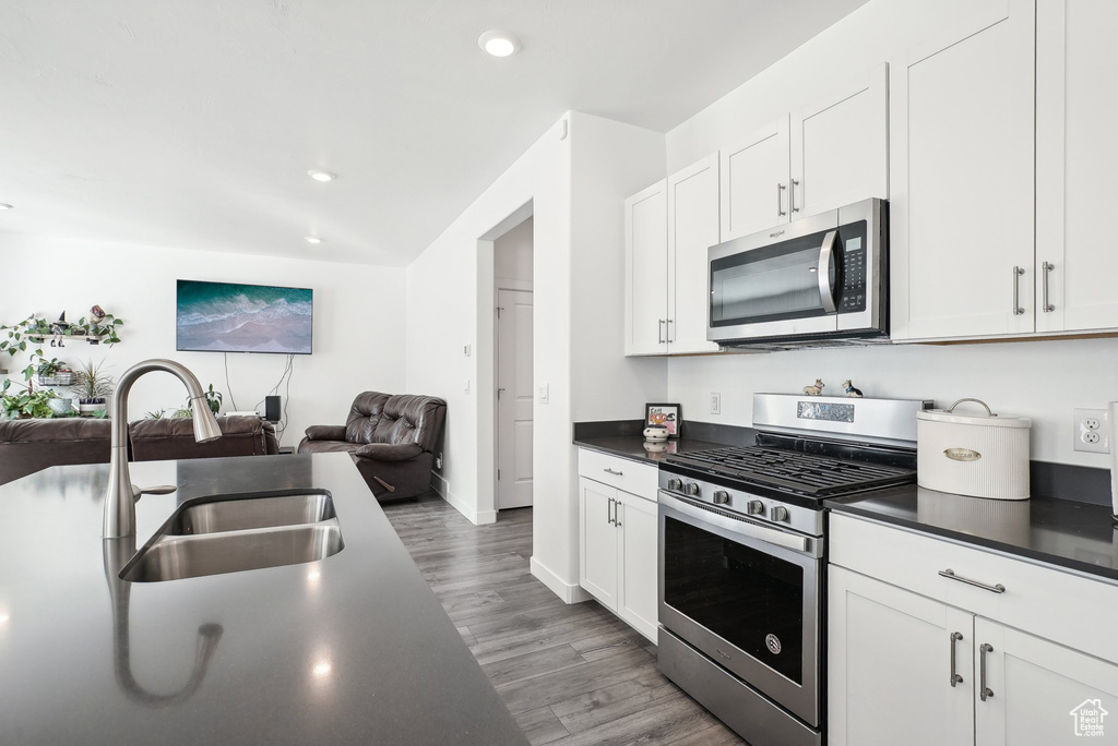 Kitchen with a sink, appliances with stainless steel finishes, dark countertops, and open floor plan
