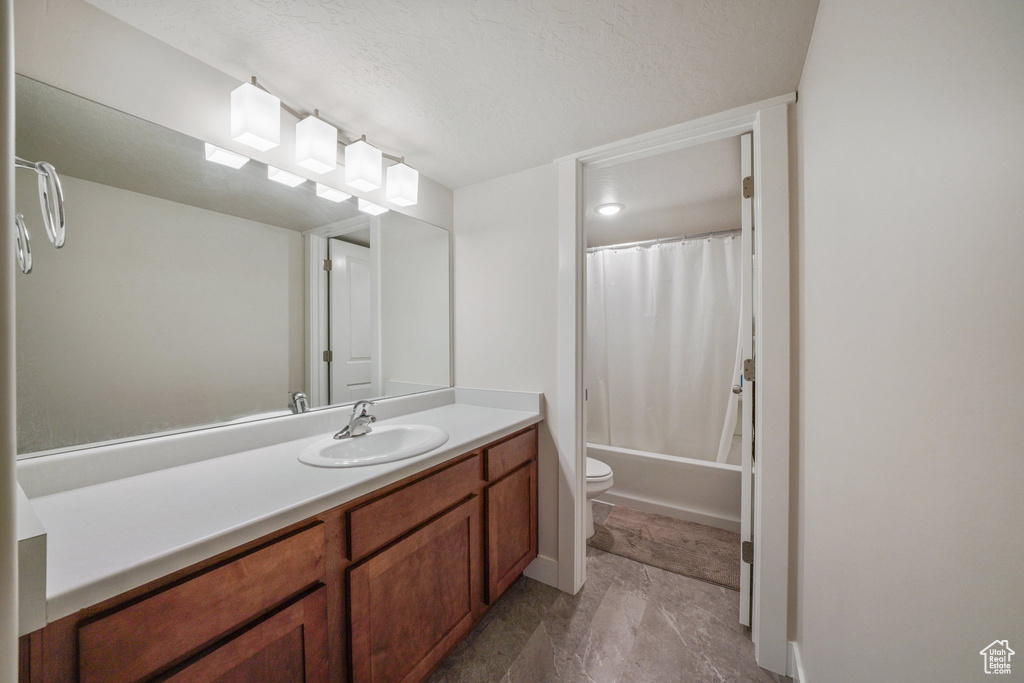 Bathroom with toilet, a textured ceiling, shower / tub combo, and vanity