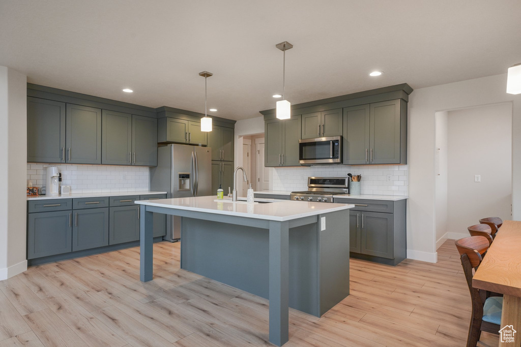 Kitchen featuring a sink, appliances with stainless steel finishes, decorative backsplash, and light countertops