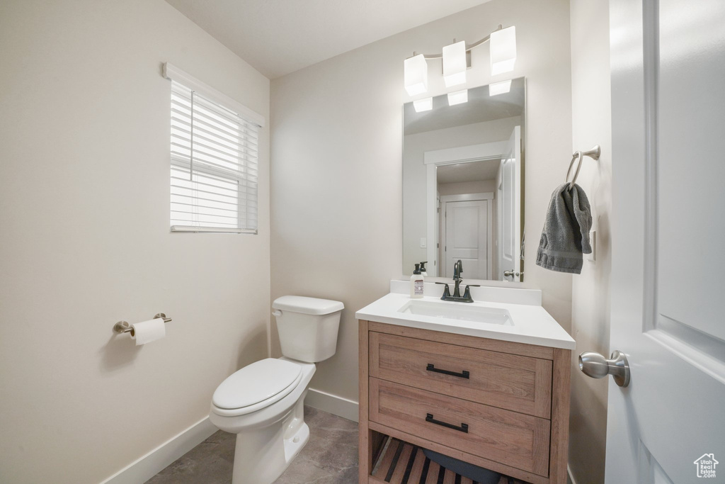 Bathroom featuring baseboards, vanity, and toilet