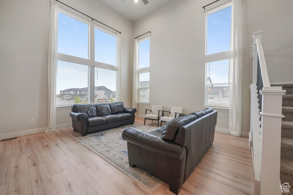 Living room featuring plenty of natural light, light wood-style flooring, ceiling fan, and stairway