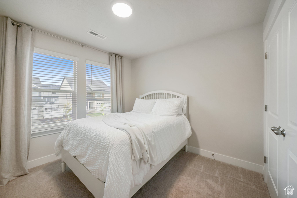 Bedroom featuring light colored carpet, baseboards, and visible vents