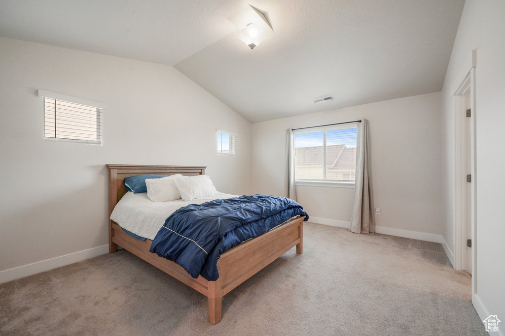 Bedroom with visible vents, baseboards, lofted ceiling, and light carpet