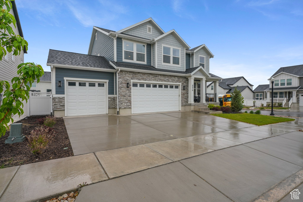 Craftsman house featuring a garage, fence, stone siding, an attached garage, and driveway