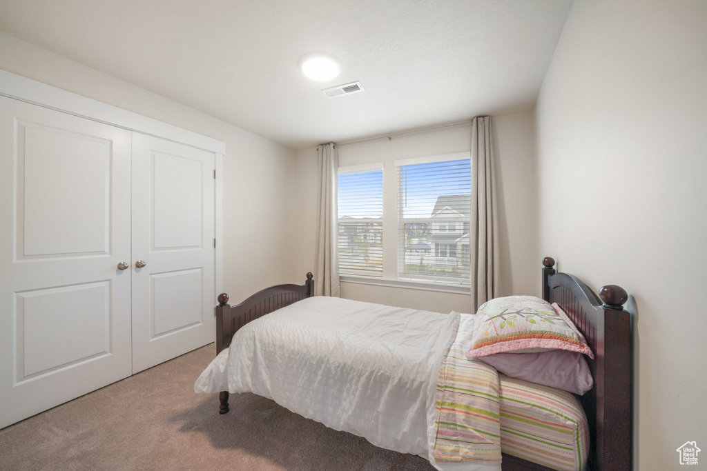Bedroom featuring carpet floors, visible vents, and a closet