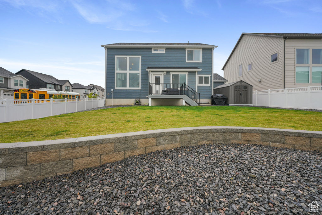 Back of property with a fenced backyard, an outbuilding, a lawn, and a shed