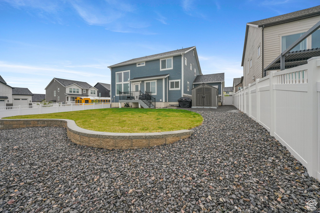 Back of house featuring a storage shed, a residential view, an outbuilding, a fenced backyard, and a yard