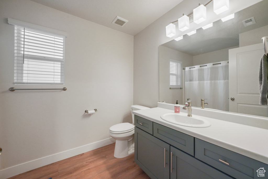 Full bath featuring baseboards, wood finished floors, visible vents, and toilet