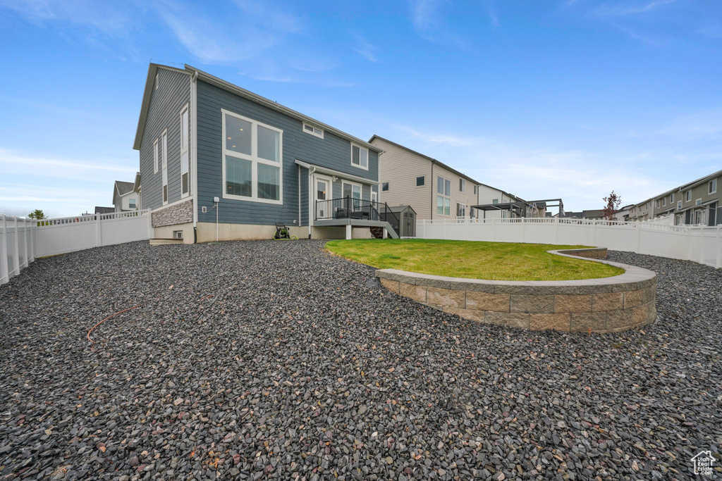 Rear view of property with a fenced backyard, a wooden deck, and a lawn