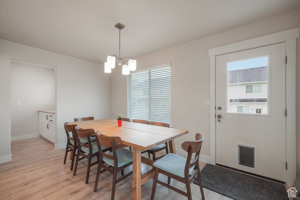 Dining area with baseboards, a notable chandelier, light wood-style flooring, and visible vents