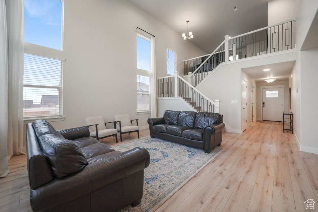 Living room featuring stairs, a high ceiling, a chandelier, and hardwood / wood-style flooring