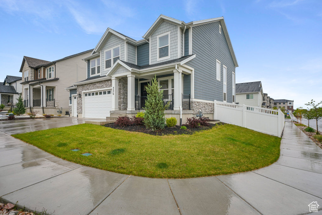 Craftsman inspired home featuring fence, a front yard, stone siding, and concrete driveway