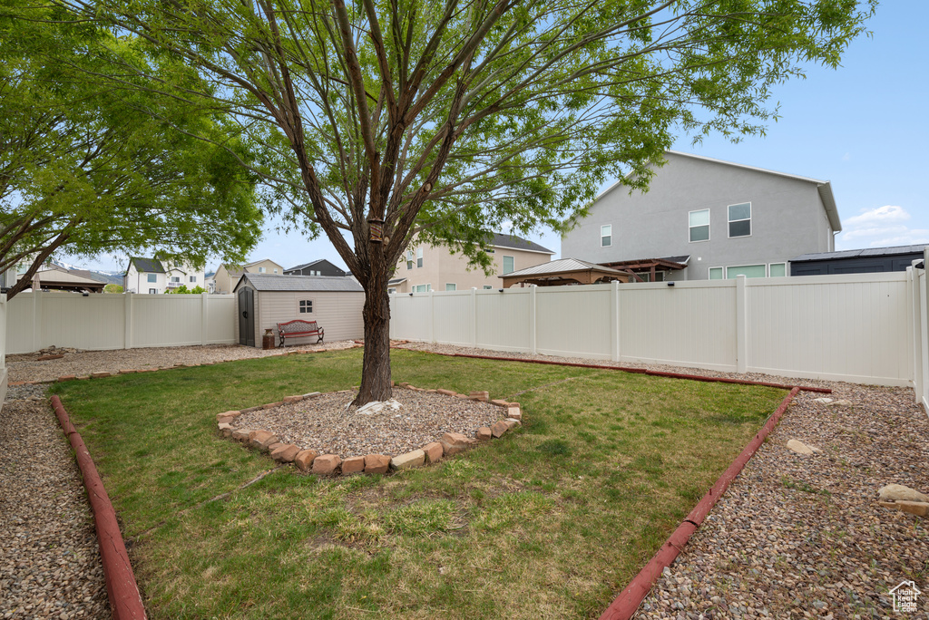 View of yard featuring a storage shed, an outdoor structure, and a fenced backyard