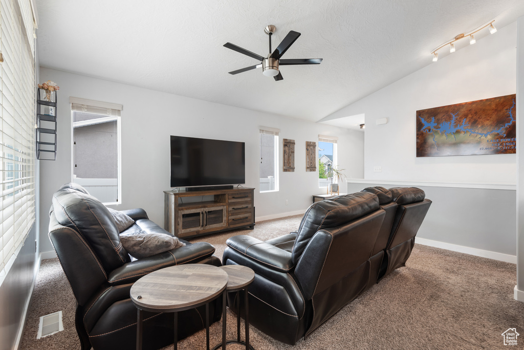 Living room with baseboards, carpet, ceiling fan, and vaulted ceiling
