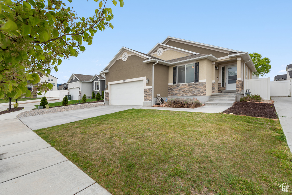 Craftsman house with fence, an attached garage, stone siding, stucco siding, and driveway