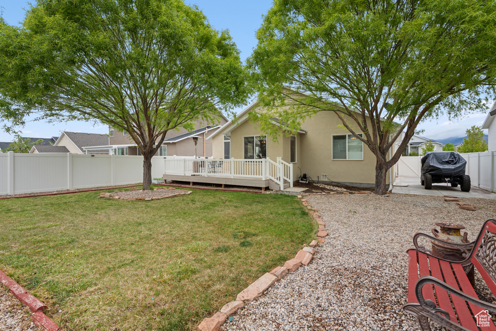 Exterior space featuring a lawn, a wooden deck, a fenced backyard, and stucco siding