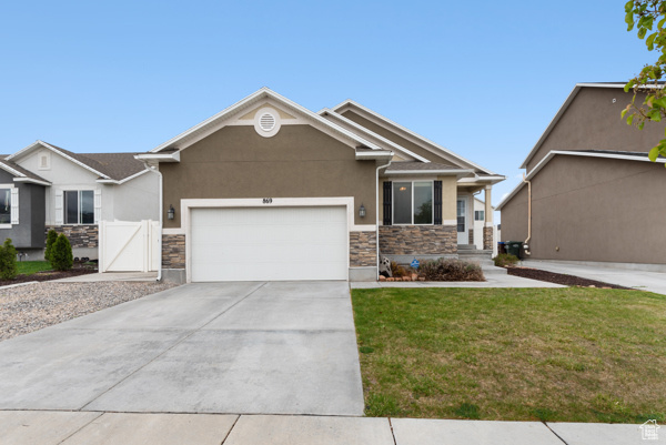 View of front of home featuring an attached garage, driveway, stone siding, and stucco siding