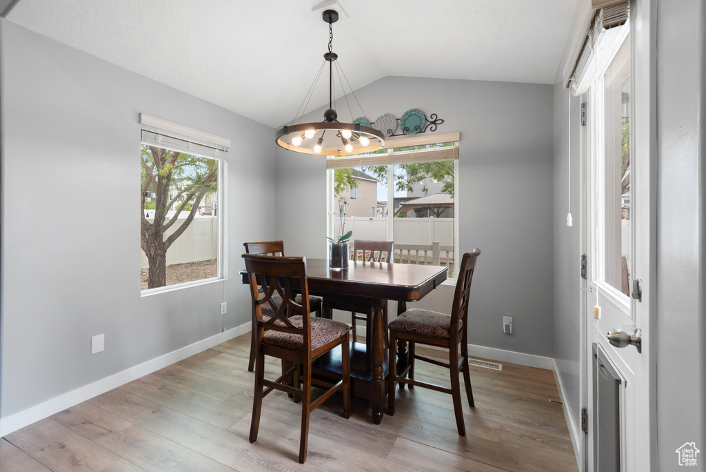 Dining space featuring visible vents, lofted ceiling, light wood-style floors, baseboards, and a notable chandelier