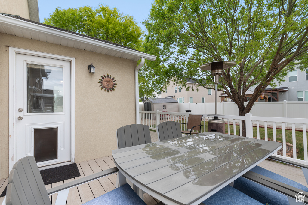 Deck with a storage shed, fence, an outbuilding, and outdoor dining space
