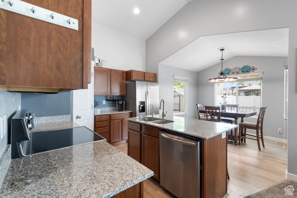 Kitchen featuring a sink, light wood-style flooring, appliances with stainless steel finishes, and lofted ceiling