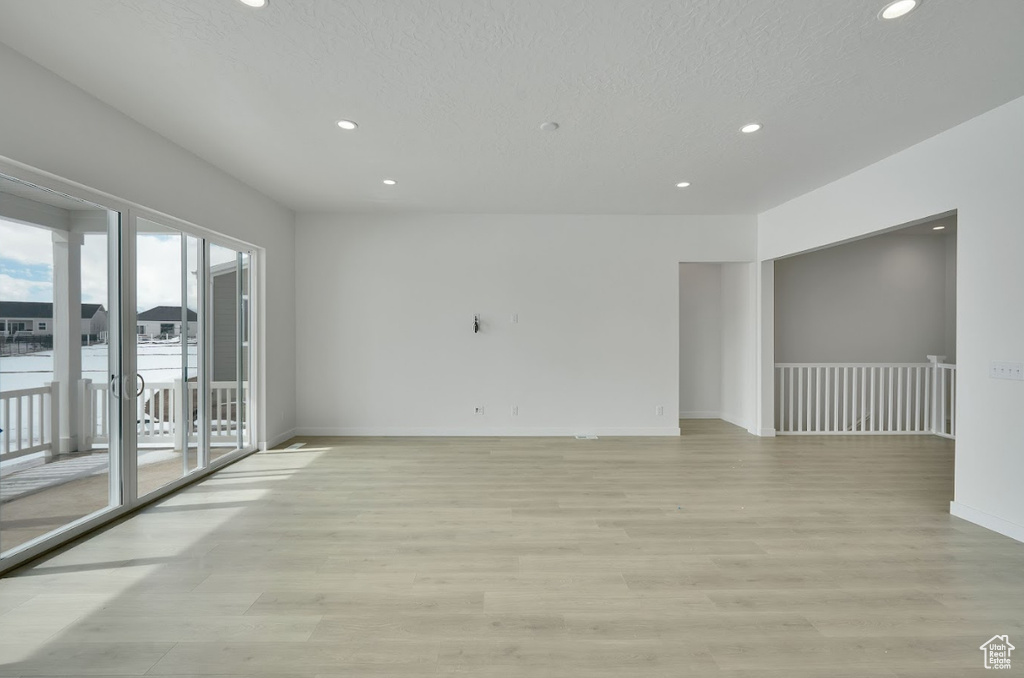 Spare room with recessed lighting, baseboards, light wood finished floors, and a textured ceiling
