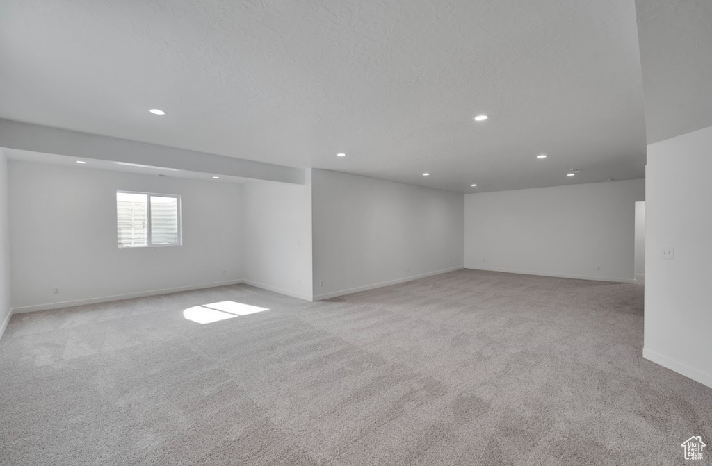 Basement with baseboards, recessed lighting, and light colored carpet