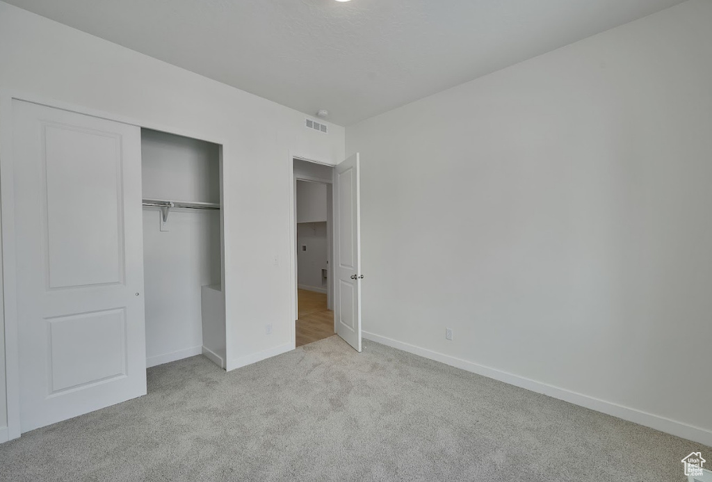 Unfurnished bedroom featuring baseboards, carpet, a closet, and visible vents