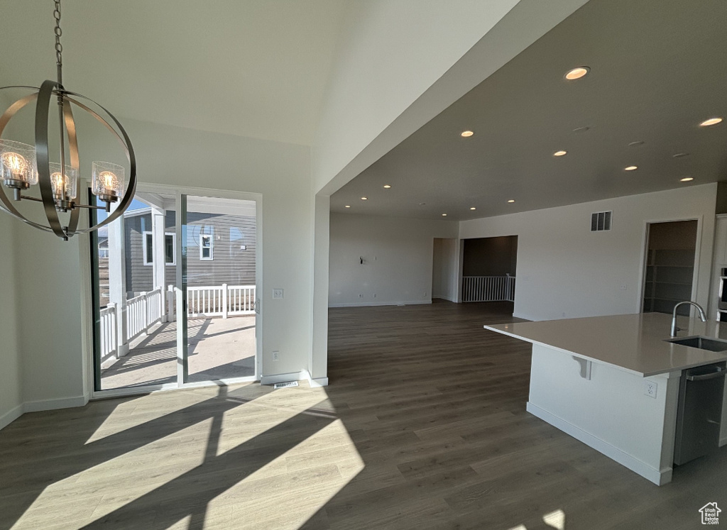 Unfurnished dining area featuring visible vents, a sink, baseboards, a notable chandelier, and dark wood-type flooring