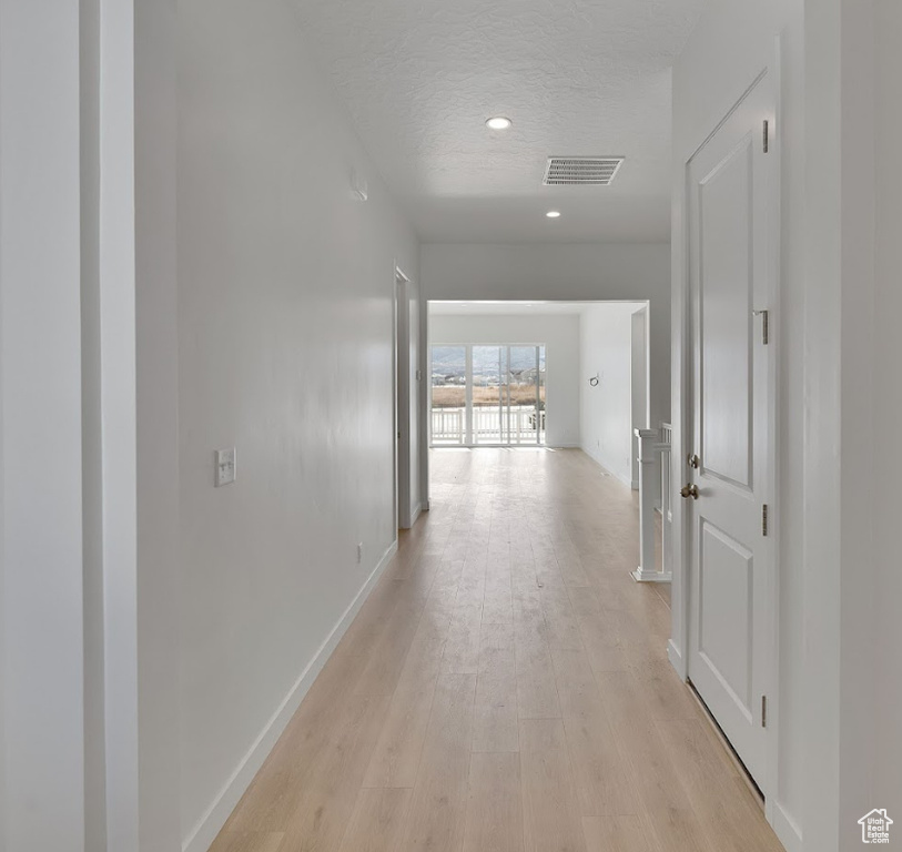 Corridor with visible vents, baseboards, recessed lighting, a textured ceiling, and light wood-style flooring