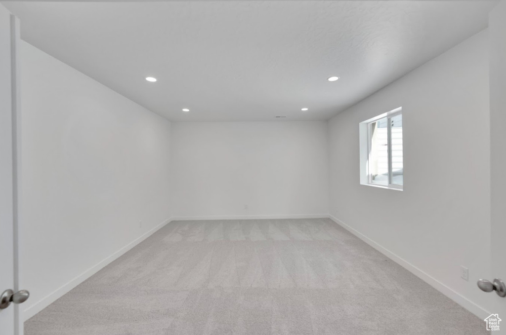 Spare room featuring baseboards, light carpet, and recessed lighting