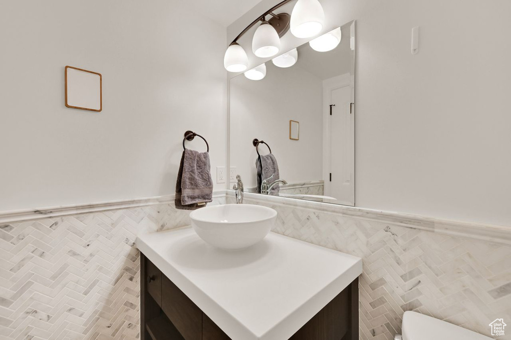Bathroom featuring toilet, tile walls, wainscoting, and vanity