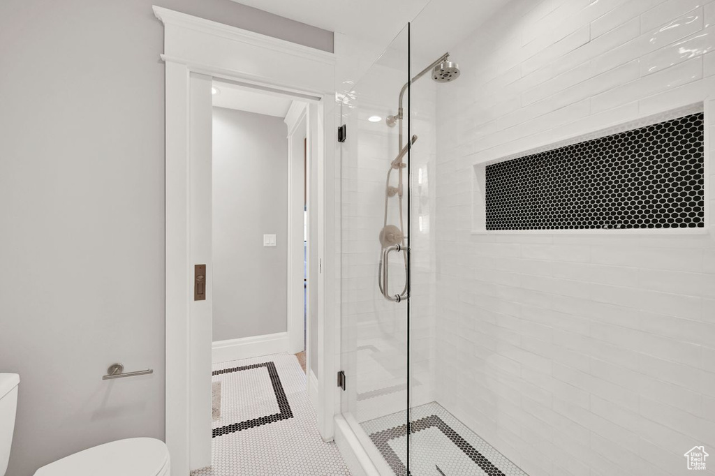 Bathroom featuring baseboards, tile patterned floors, a stall shower, and toilet