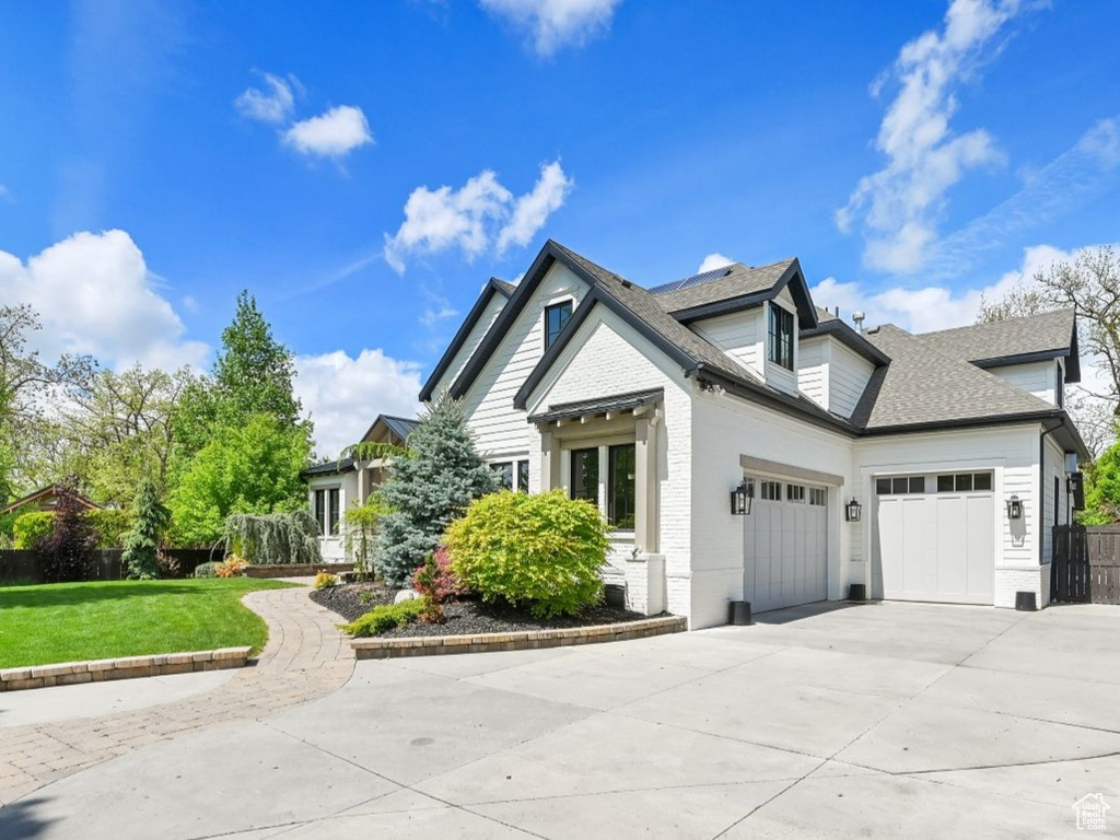 View of front of property featuring fence, a front yard, brick siding, an attached garage, and driveway